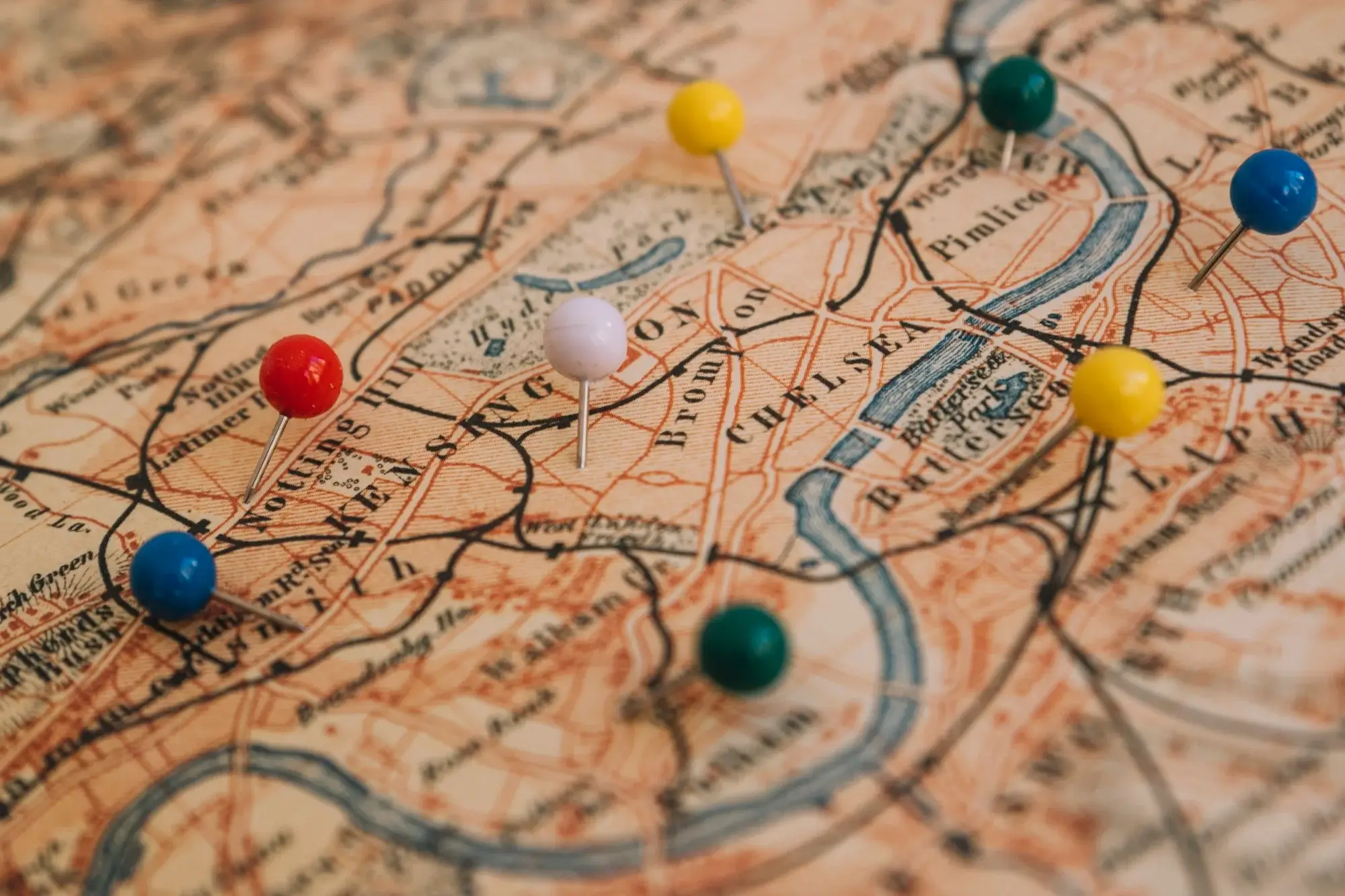 Vintage paper map with coloured pins marking multiple locations across a city, used to illustrate service coverage areas